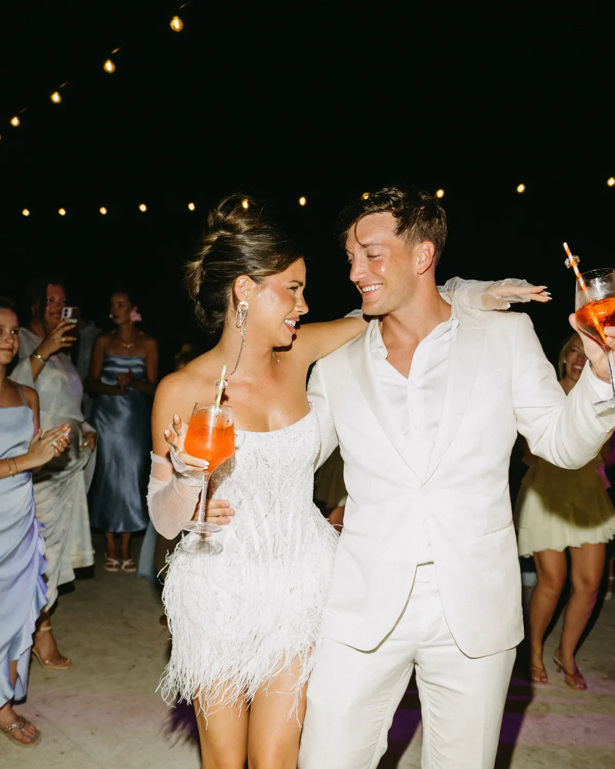 A bride and groom on the dance floor, drinks in hand, at their reception
