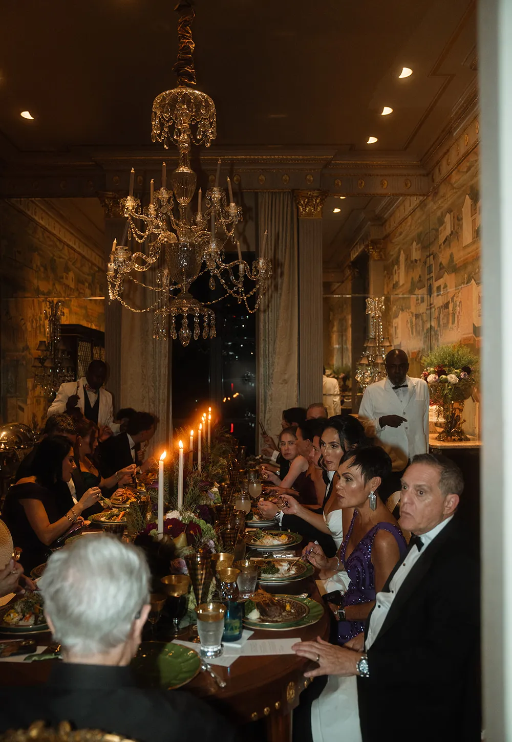 A candlelit wedding reception dinner under a chandelier