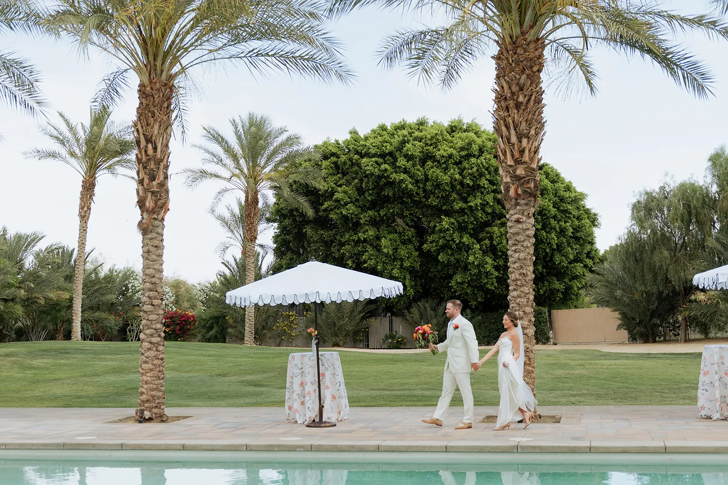 A poolside wedding reception set beneath palm trees