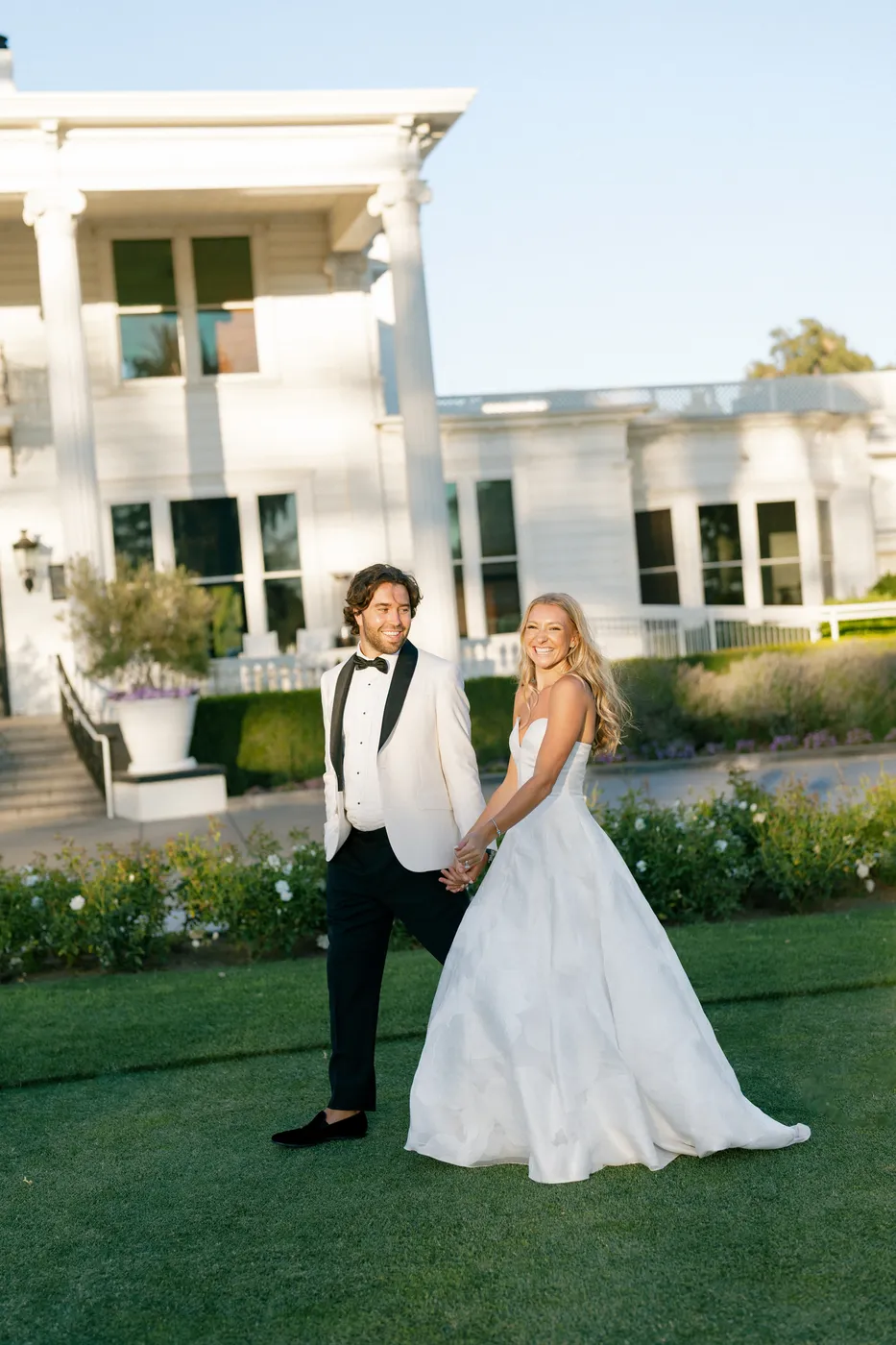 A bride and groom outside the white estate house at their Napa wedding