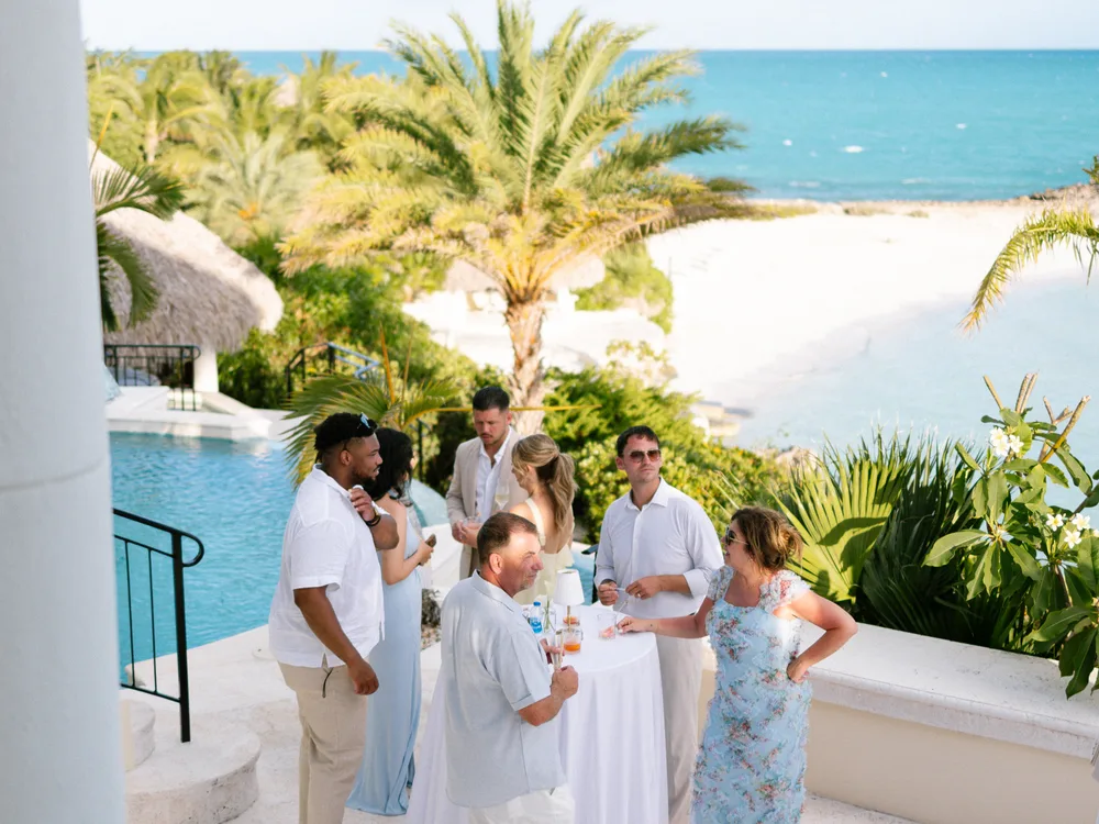 Guests at a poolside welcome party overlooking the ocean